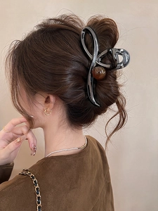 Detailed view of a dark grey spiral hair claw clip with amber bead in a chic updo
