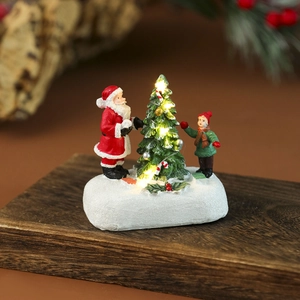 Maison en résine lumineuse détaillée avec Père Noël et enfants sur socle enneigé déco
