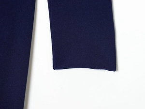 Close-up of navy blue pleated dress fabric with detailed grain texture and fine stitching