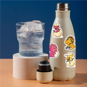 Waterproof cartoon dinosaur stickers applied on a beige metal water bottle on a podium