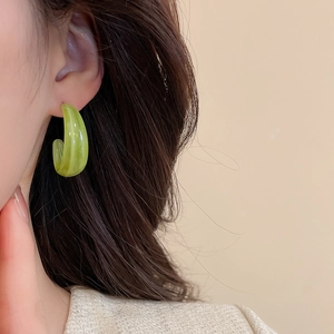 Vue rapprochée des boucles d'oreilles en C acrylique vert translucide avec effet marbré