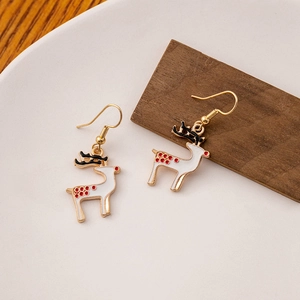 Detailed close-up of white enamel Christmas reindeer earrings with red polka dots and gold hooks