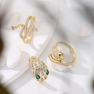 Detail of snake ring in gold-plated brass with white zircon and green gemstone eyes