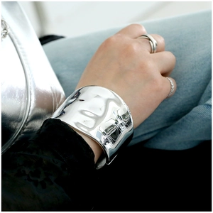Close-up of wide polished silver metal cuff bracelet with shiny geometric irregular design