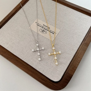 Detailed view of silver cross pendant necklaces with white pearls and sparkling crystals