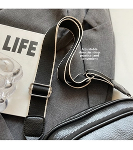 Detail of adjustable black and white wide fabric strap with silver buckle on leather bag