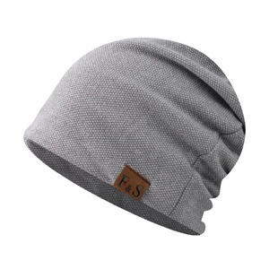 Close-up of grey knit beanie fabric and F&S brown leather brand tag detail