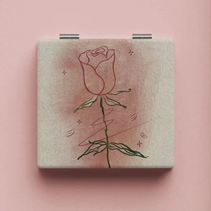 Macro detail of square foldable makeup mirror with minimalist red rose line art pattern