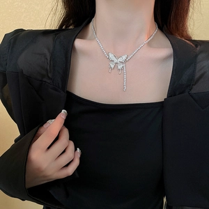 Macro shot of silver butterfly pendant with rhinestone wings and elegant tassel detail
