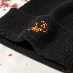 Close-up of orange pumpkin embroidery on black ribbed knit beanie for Halloween