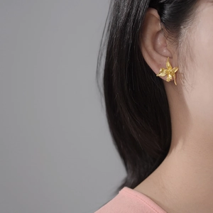 Detailed view of handmade S925 silver iris flower earrings on model in gold finish