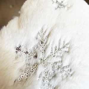 Close-up of white faux fur Christmas tree skirt with shimmering silver sequin snowflakes