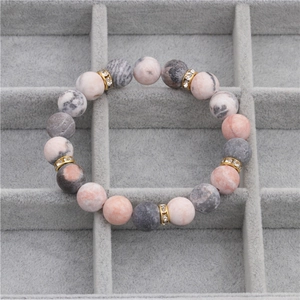 10mm matte pink spotted stone beaded bracelet with gold rhinestone spacers on a tray
