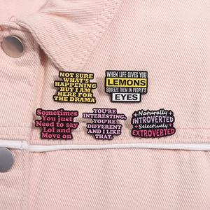 Detail of colorful enamel quote pins styled on a pastel pink denim jacket lapel
