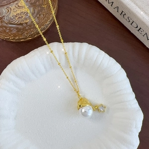 French romantic gold necklace with pearl pendant and crystal star charm on ceramic tray