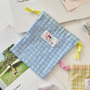 Detail of blue and yellow checkered cotton drawstring bags with cute fabric patch label