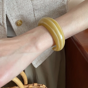 Detailed view of amber acrylic bangle with white marble texture on a person wrist