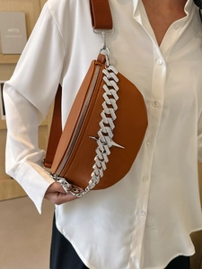 Detail of brown lychee leather chest bag with chunky silver chain and star charm