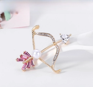 Macro detail of Cupid arrow brooch with pink glass, pearl and sparkling crystals