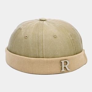 Detail of khaki miki hat featuring a silver metal letter R logo and corduroy rolled edge
