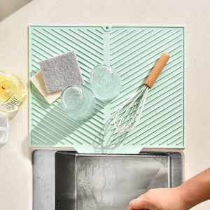 Light green silicone drying mat with diagonal drainage ridges for kitchen countertops