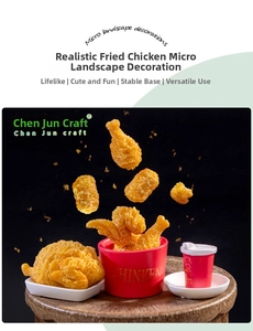Gros plan de morceaux de poulet frit miniature en résine tombant dans un seau rouge