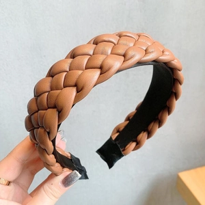 Hand holding a brown braided PU leather headband with black fabric inner lining detail