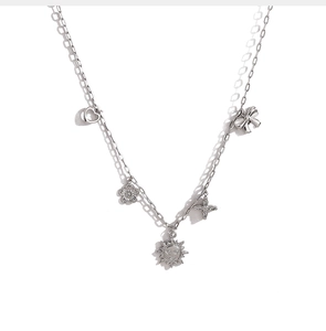 Détail d'un collier argenté avec pendentifs en forme de soleil et de cœur