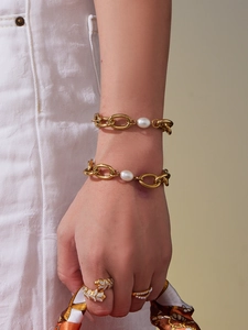 Close-up of hand wearing layered 18k gold plated chains, pearl bracelets and snake ring