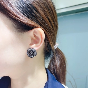 Elegant black camellia flower stud earrings with sparkling cubic zirconia on model ear