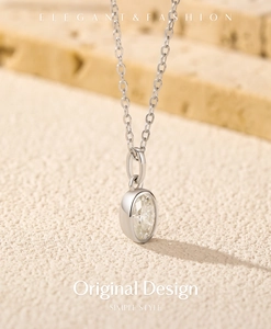 Vue détaillée du pendentif moissanite ovale sur chaîne en argent et fond en pierre élégant