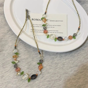 Detail of colorful beaded floral necklace with transparent flower and leaf pendants in a dish