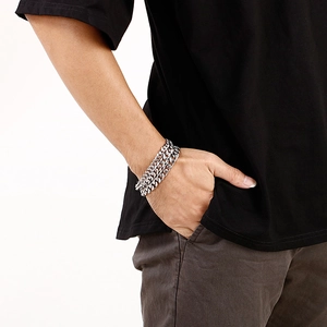 Close-up of triple layered silver stainless steel Cuban link bracelets on male wrist