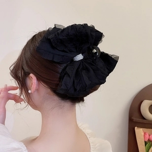 Détail d'une grande pince à cheveux noeud noir avec strass argentés et tissu doux