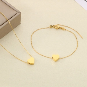Détail d'un ensemble collier et bracelet avec pendentif cœur plaqué or 18k sur fond texturé