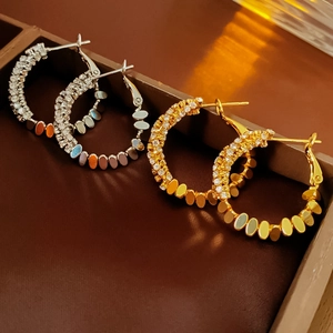 Detailed close-up of gold and silver pave zircon earrings in a premium jewelry box