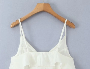 Detailed close-up of white layered ruffle camisole top on a wooden hanger with thin straps