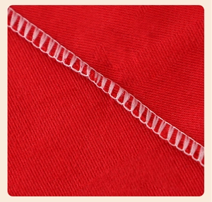 Close-up of red herringbone fabric with white overlock stitching on the Christmas hat