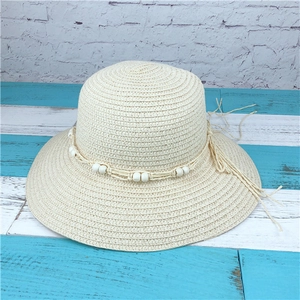 Detail of cream straw sun hat with decorative white beads and elegant long tassels