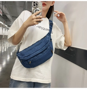 Detail of dark blue denim crossbody bag with adjustable strap and metallic zipper closure