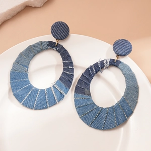 Detailed view of large oval denim fabric hoop earrings with blue gradient texture