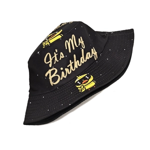 Detail of black bucket hat featuring gold It's My Birthday text and a yellow duckling icon