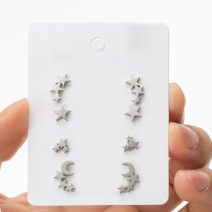 Detailed view of four pairs of stainless steel star and moon stud earrings on a card