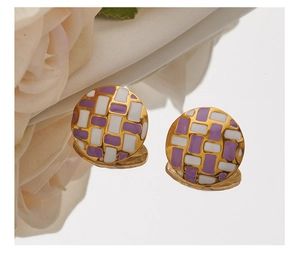 Detail of round gold earrings with purple and white checkered enamel on mirror surface