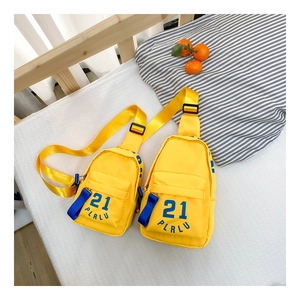 Détail de deux sacs de poitrine jaunes pour enfants avec des imprimés bleus sur lit