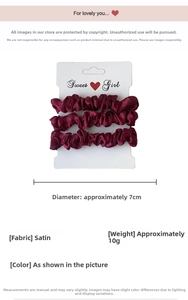 Close-up of three dark red satin hair scrunchies on a Sweet Girl branded white card