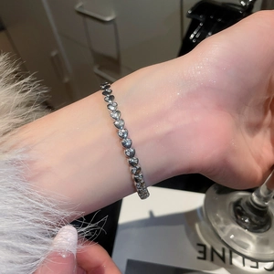 Macro detail of silver heart link bracelet with sparkling pavé zircons on woman's wrist
