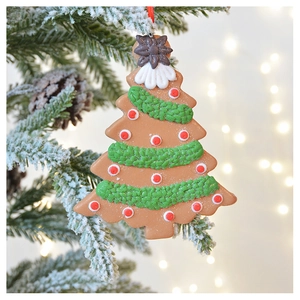 Detail of a gingerbread-style Christmas tree ornament hanging on a snowy branch
