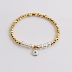 Détail d'un bracelet de perles dorées avec perles blanches et pendentif œil maléfique