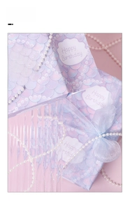 Detail of mermaid scale gift bag with Happy Birthday text, pearl chain, and blue bow